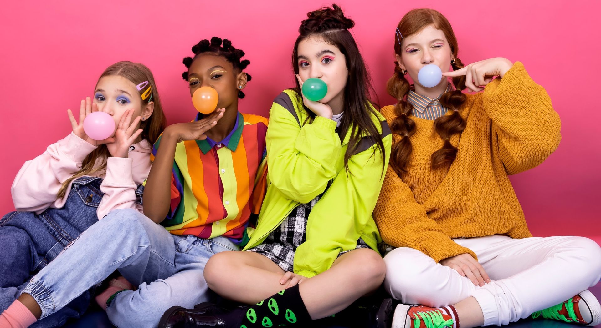 4 teenaged girls hanging out, having fun, wearing colorful clothes and blowing bubblegum